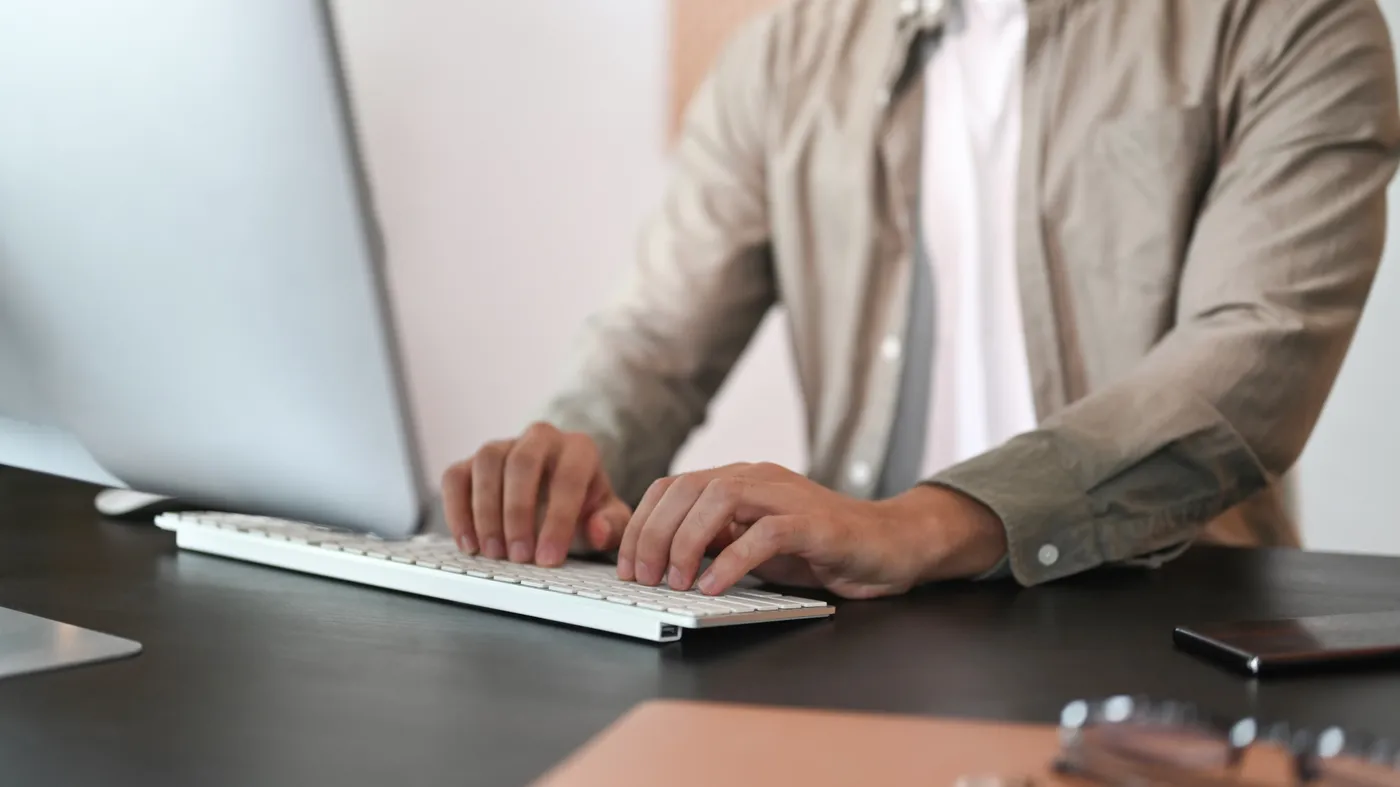 Office worker typing at a desk — wrist and hand strain from computer work